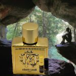 A bottle of perfume sitting in front of a cave.