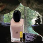 A bottle of perfume and a small container sitting in the rocks.