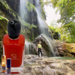 A person standing in front of a waterfall with a camera.