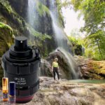 A person standing in front of a waterfall with a camera.