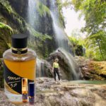 A person standing in front of a waterfall next to a bottle.