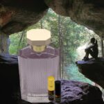 A bottle of perfume sitting in front of a cave.