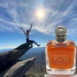 A person jumping in the air over a cliff with a bottle of perfume.