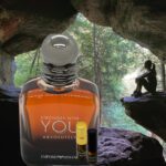 A bottle of cologne sitting in front of a cave.