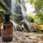 A person standing in front of a waterfall with a bottle.