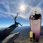 A person jumping in the air next to a bottle of perfume.