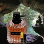 A bottle of perfume sitting next to a person in the woods.