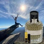 A person jumping over rocks with an empty bottle of perfume.