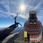 A person is jumping over the rocks with a bottle of perfume.