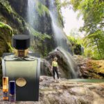 A man standing in front of a waterfall next to a bottle.