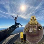 A person jumping in the air over a cliff with an open bottle of perfume.