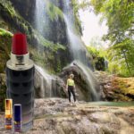 A woman standing in front of a waterfall with lipstick.