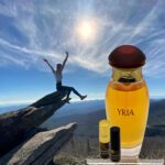 A person is sitting on the edge of a cliff with a bottle of yria.