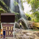 A person standing in front of a waterfall.