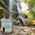 A man standing in front of a waterfall next to some rocks.